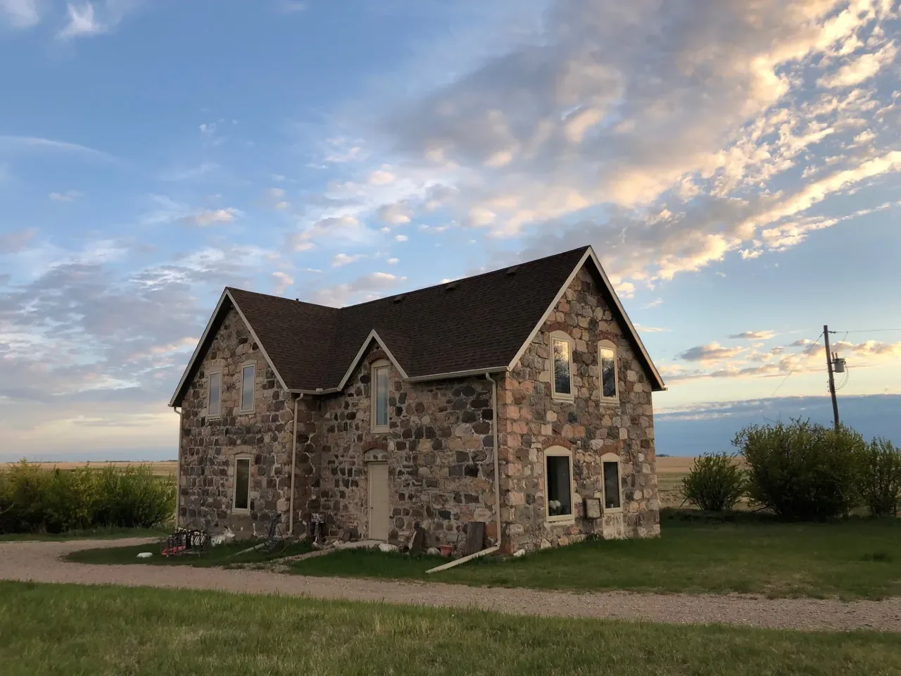 Restored stone farmhouse on the Saskatchewan prairie at golden hour